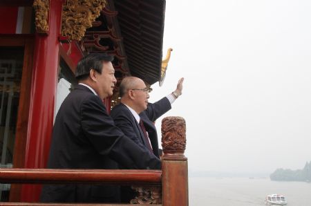 Kuomintang (KMT) Chairman Wu Poh-hsiung (R) waves to tourists on a boat on the West Lake in Hangzhou, capital of east China's Zhejiang Province, May 30, 2009. (Xinhua/Xing Guangli)